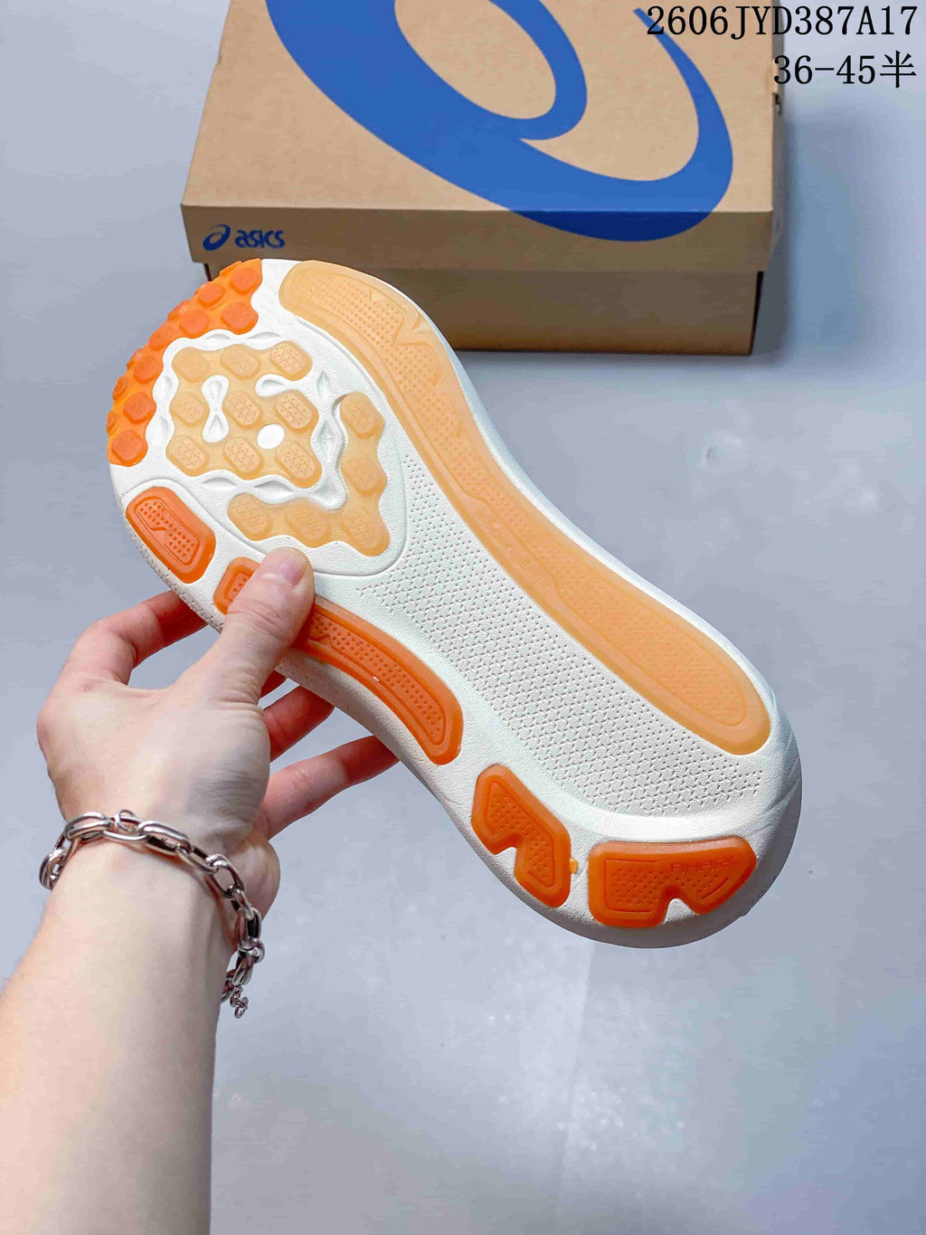 Underside of a light-colored running shoe showing orange and tan outsole sections