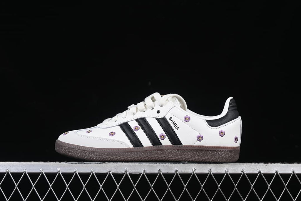 Side view of a white adidas Samba OG W with black stripes, purple flower embroidery, and dark brown outsole