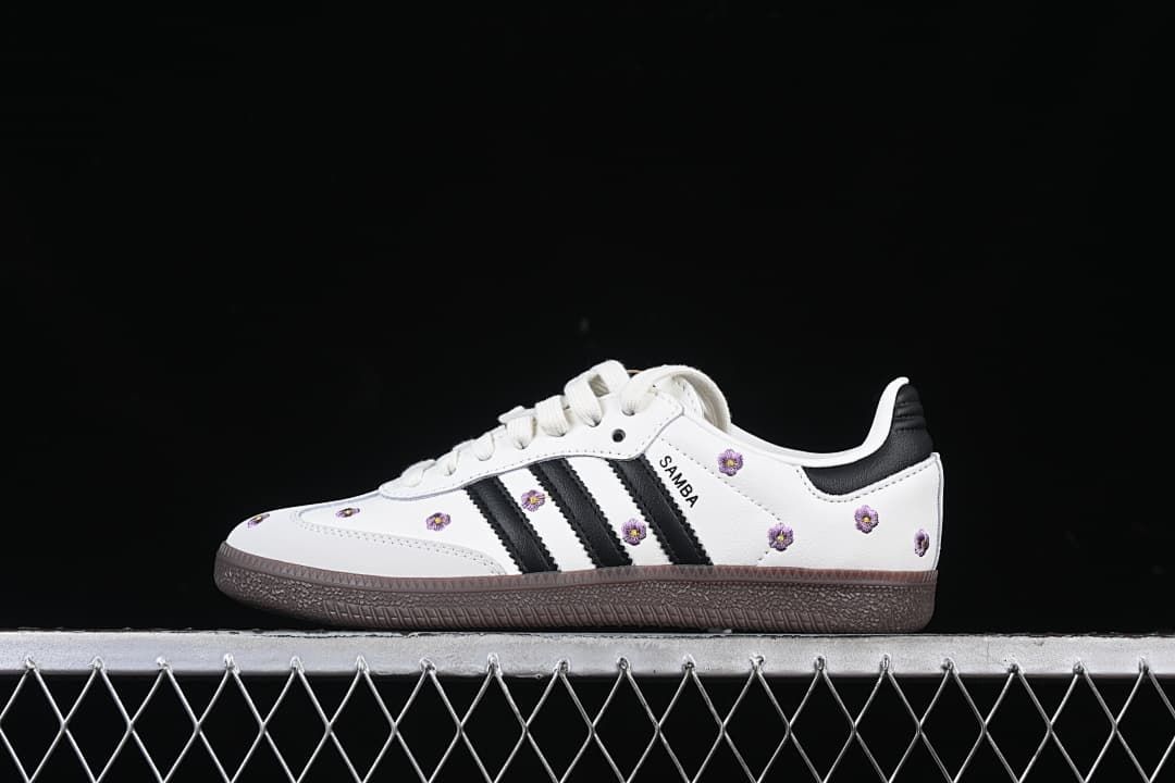 Side view of a white adidas Samba OG W with black stripes, purple flower embroidery, and dark brown outsole