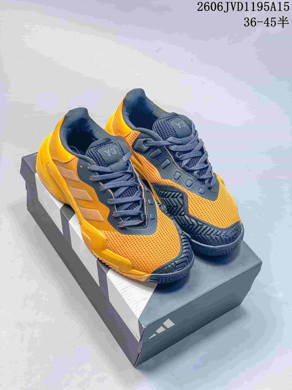 Orange and dark gray Y-3 Barricade 13 low-top sneakers, photographed as a pair on a shoe box.