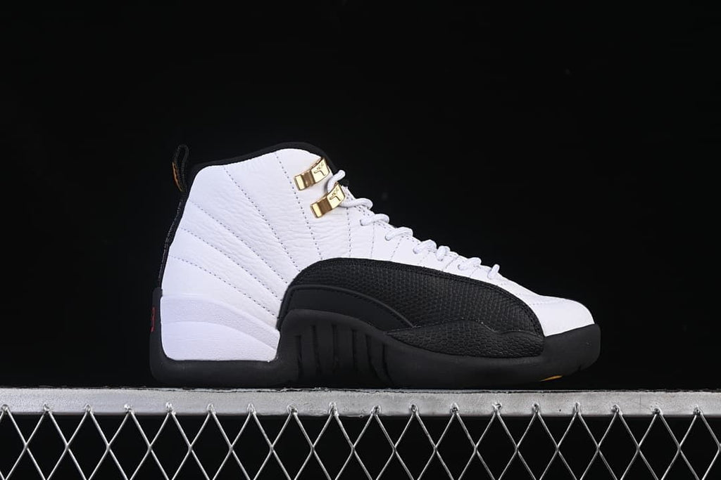 Side view of a single white and black high-top sneaker with gold-tone lace hardware.