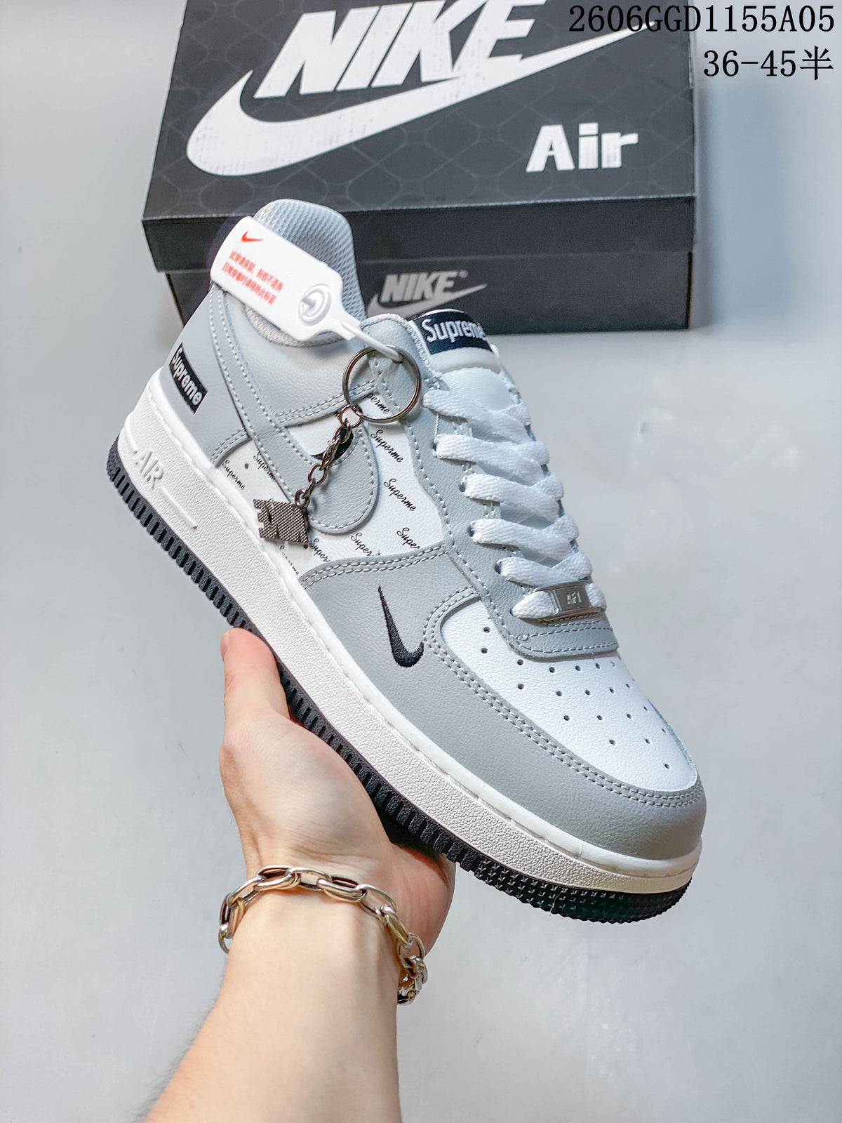 Light gray low-top sneaker with printed details, dark outsole, and a hanging charm