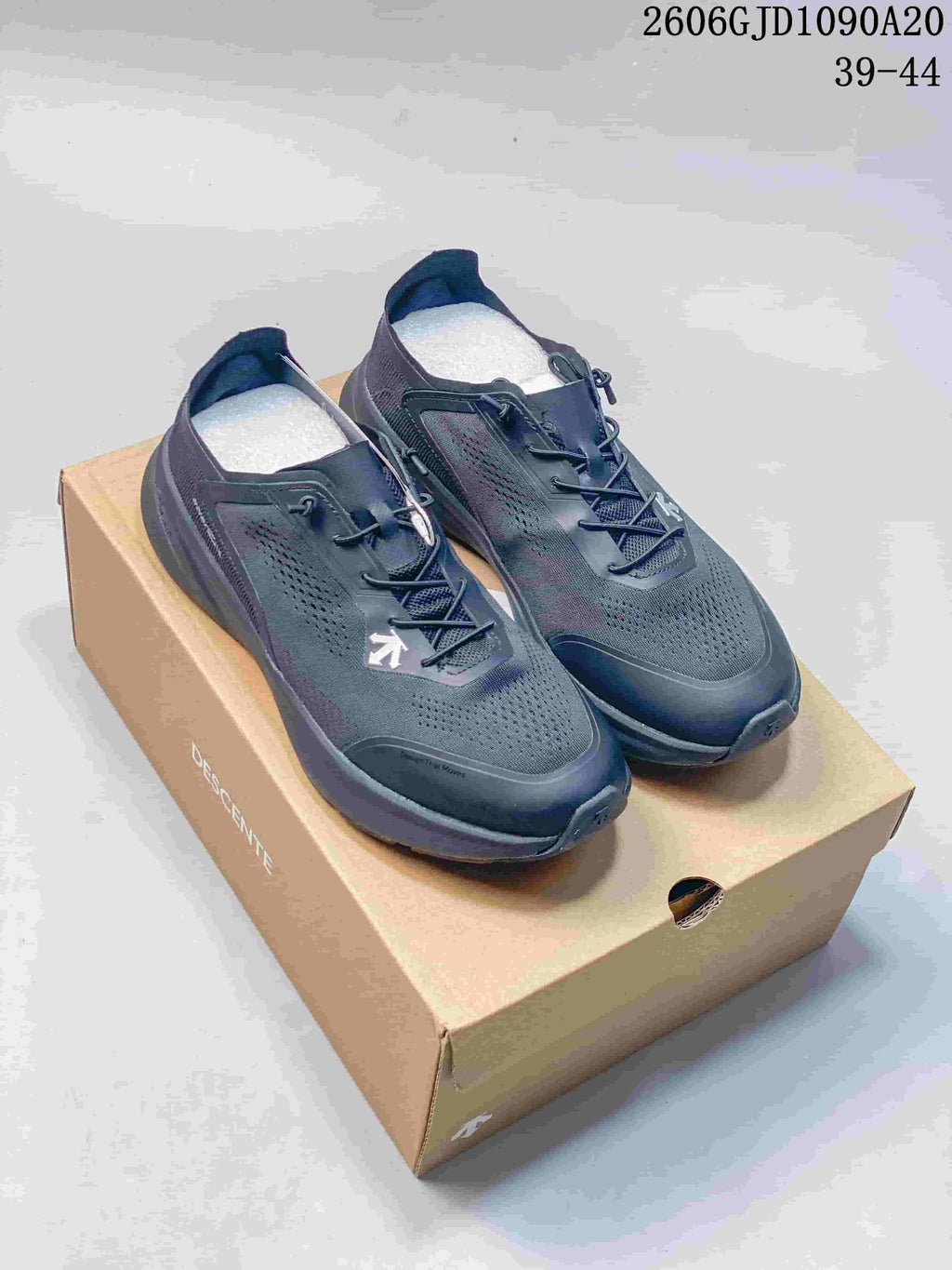 Pair of dark gray Descente low-top running shoes on a branded shoebox