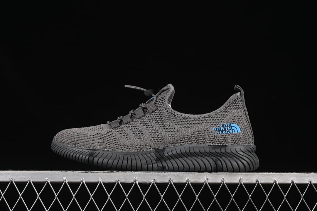 Side view of the gray shoe with blue logo accents and a dark grooved outsole