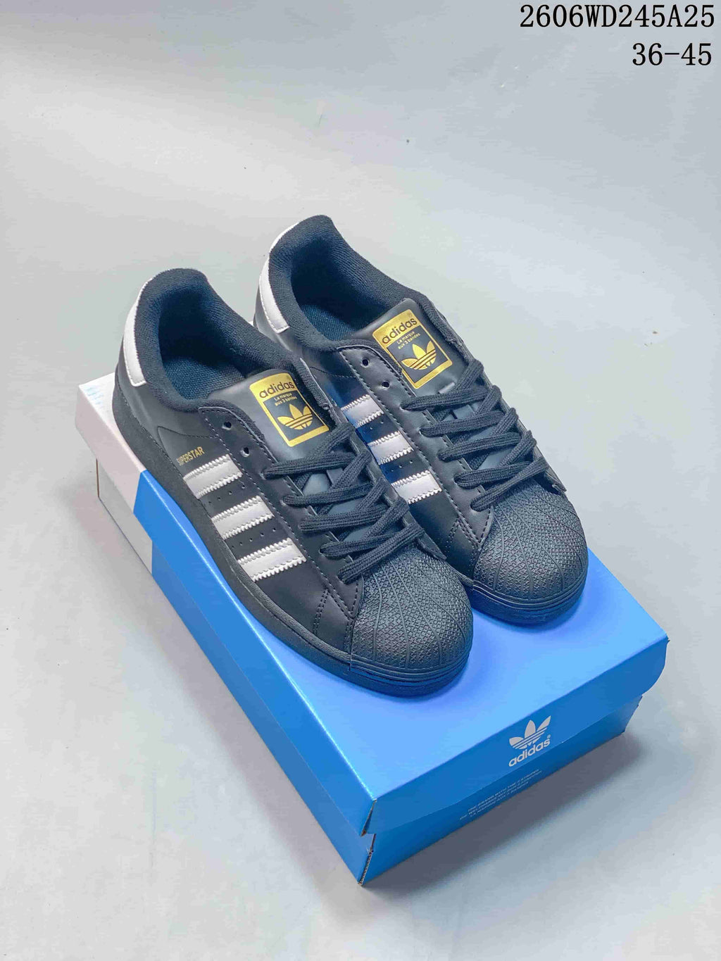 Pair of dark gray adidas Superstar sneakers with white stripes and textured shell toes