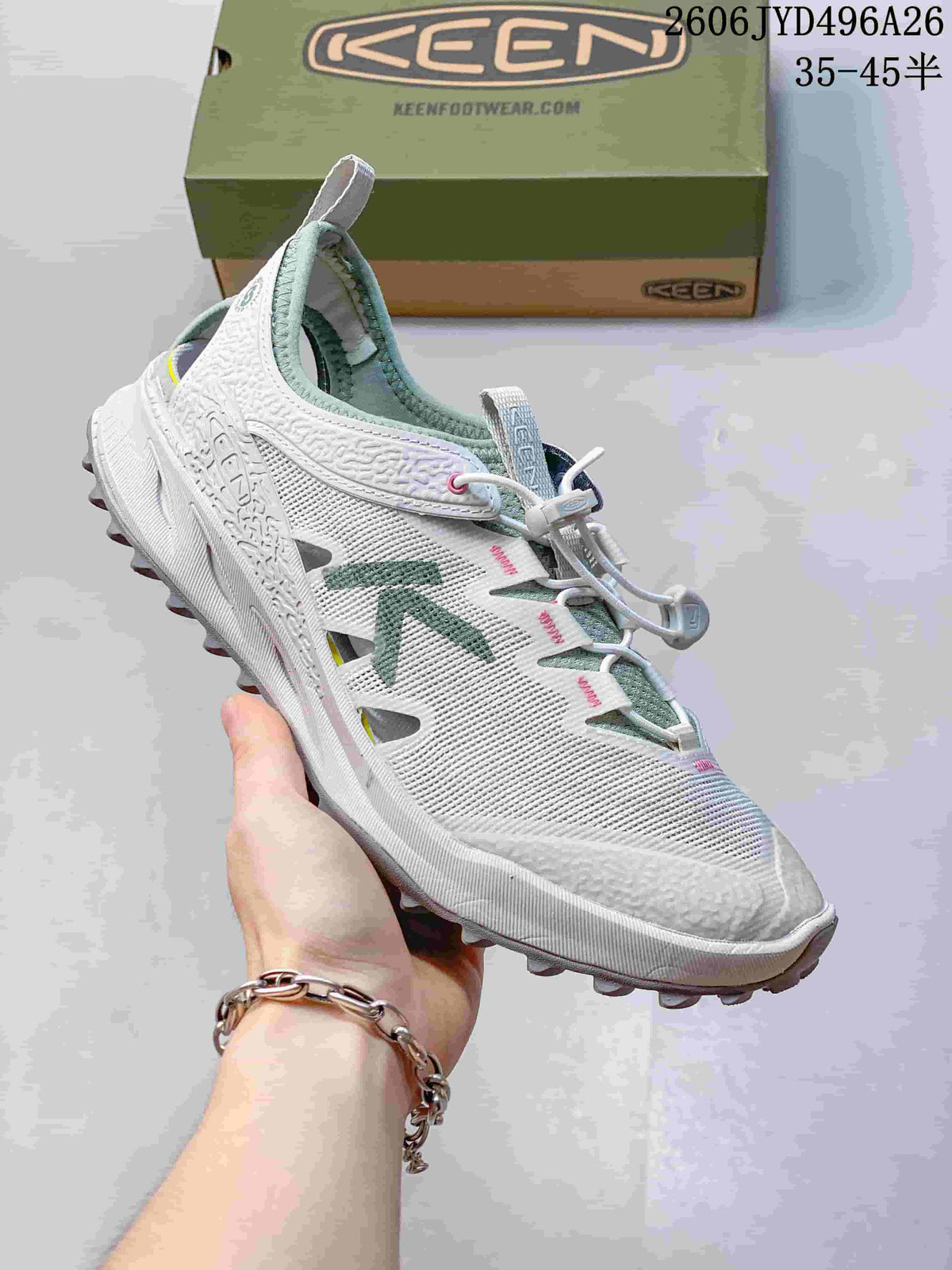 Side view of a white low-top hiking shoe with green accents and quick lacing