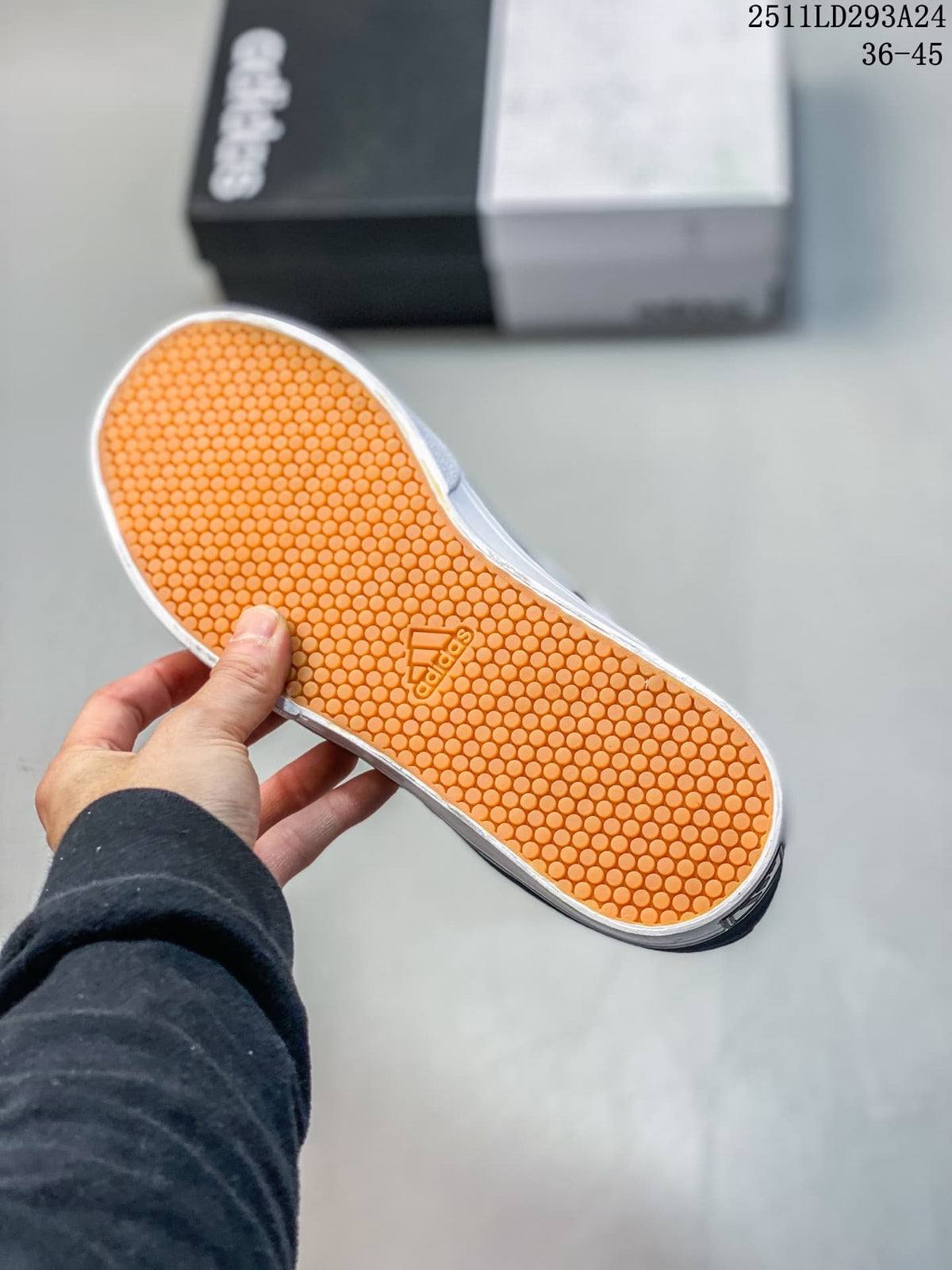 Textured orange outsole of the navy Adidas sneaker.
