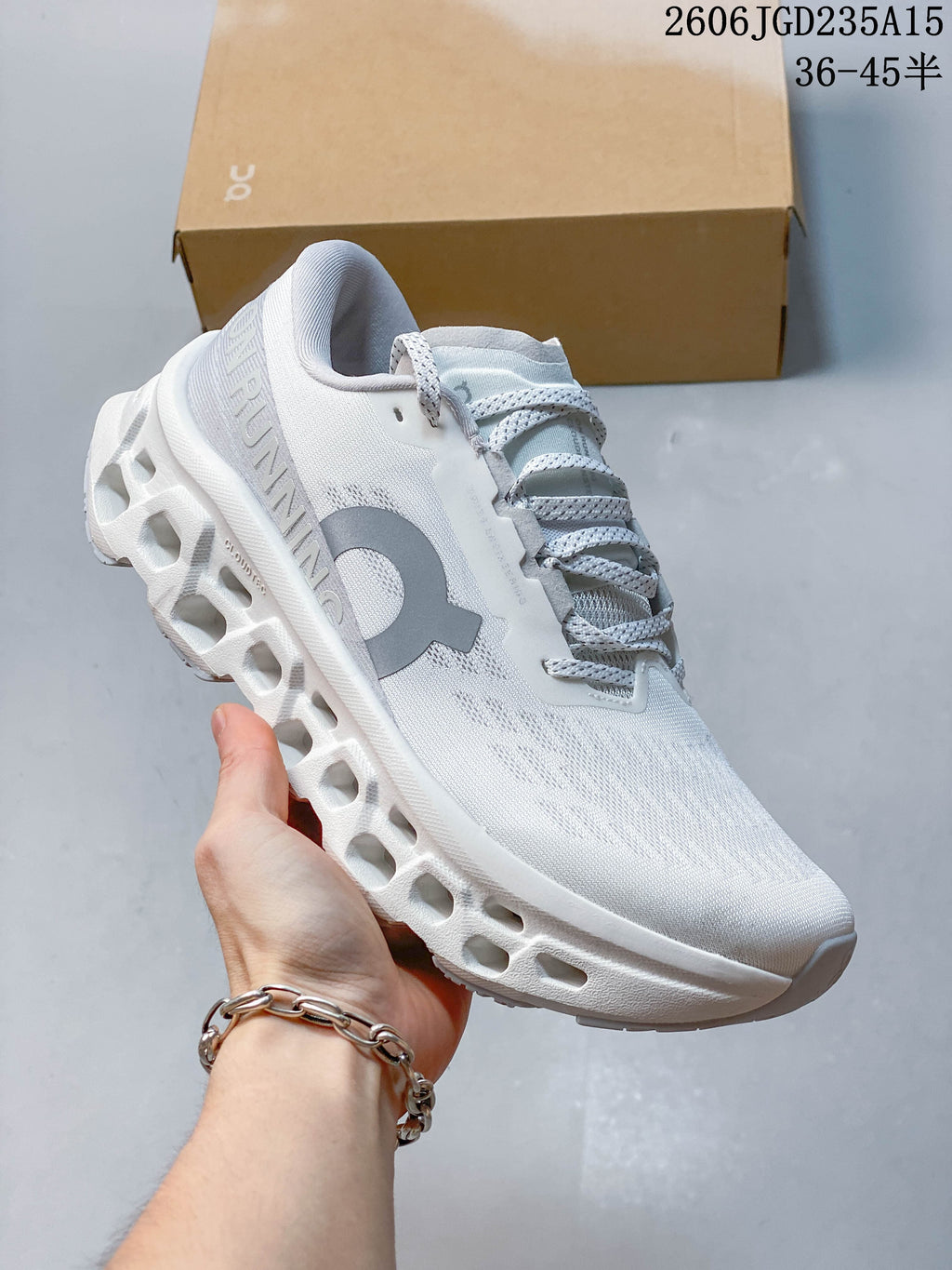 Angled side view of a white On Cloudmonster 3 sneaker with gray logo detailing