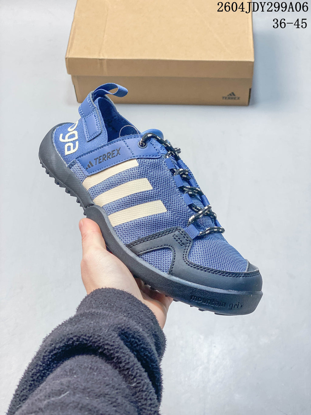 Angled side view of a blue Adidas outdoor shoe with cream stripes and dark accents