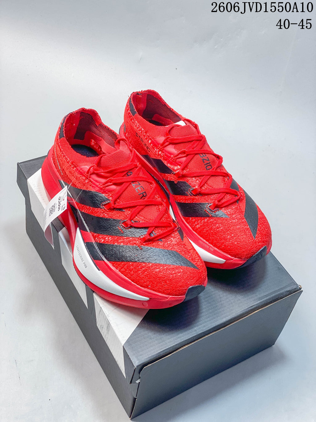 Red and black adidas Adizero Prime X3 running shoes displayed on a shoebox.