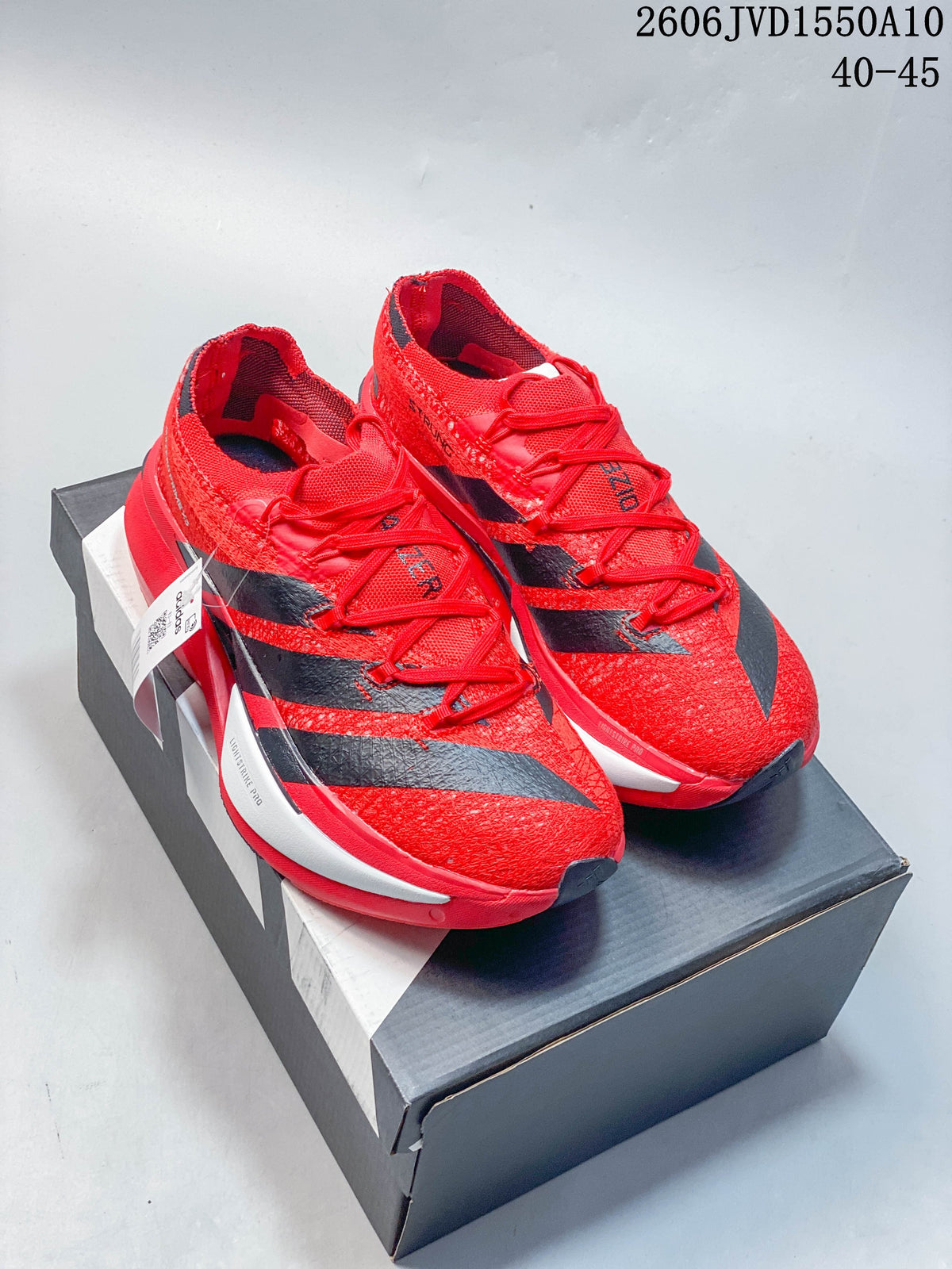 Red and black adidas Adizero Prime X3 running shoes displayed on a shoebox.