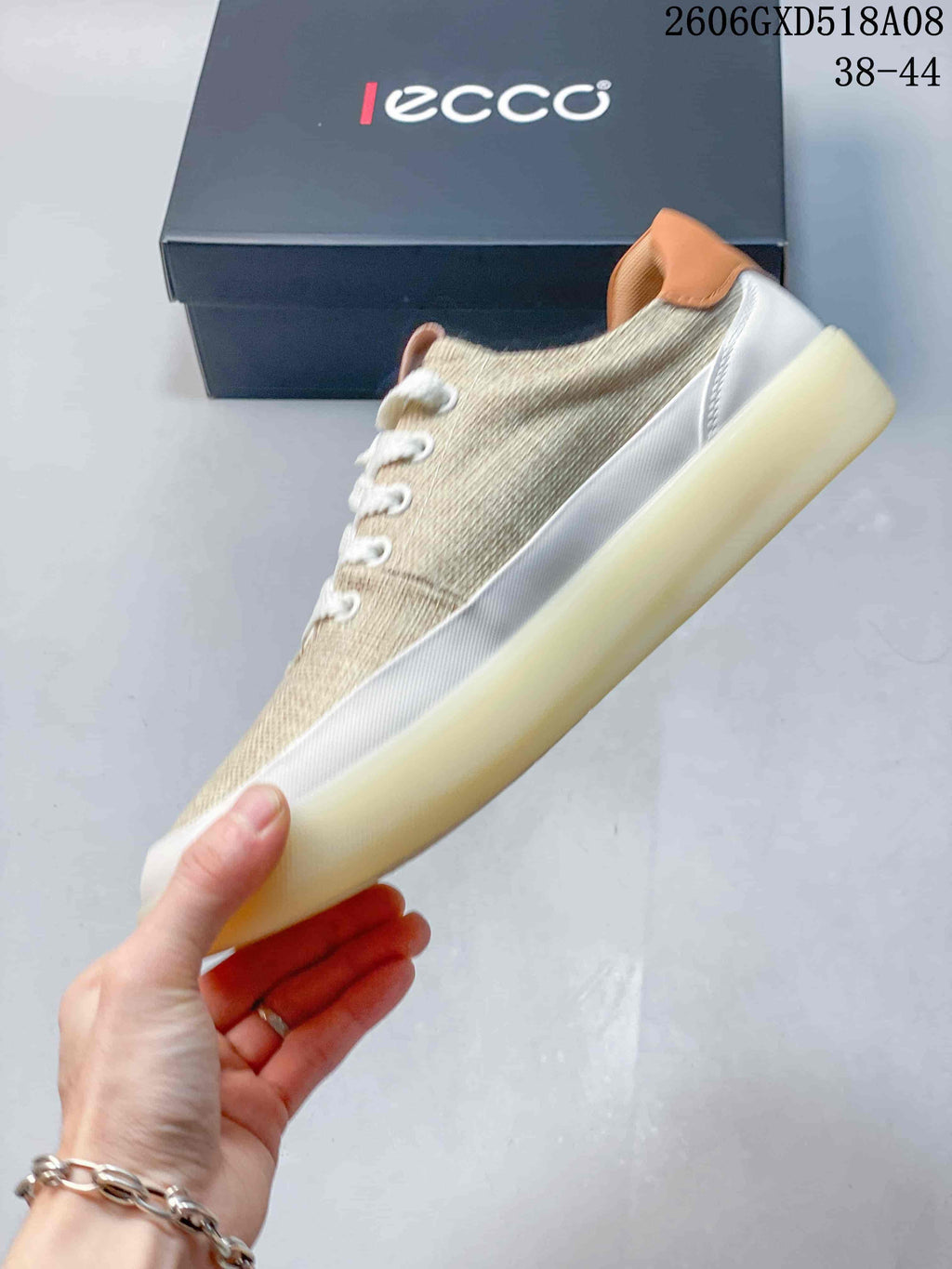 Side profile of a beige lace-up sneaker with white trim and a light-colored sole.