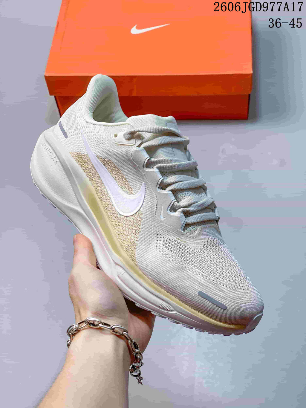 Close side view of an off-white Nike Air Zoom Pegasus 41 shoe with pale gold accents and a white Swoosh.