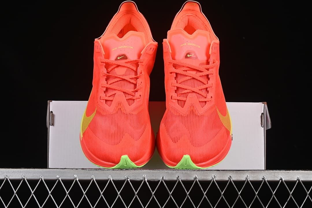 Front view of the pair with coral-orange uppers and yellow-green accents.