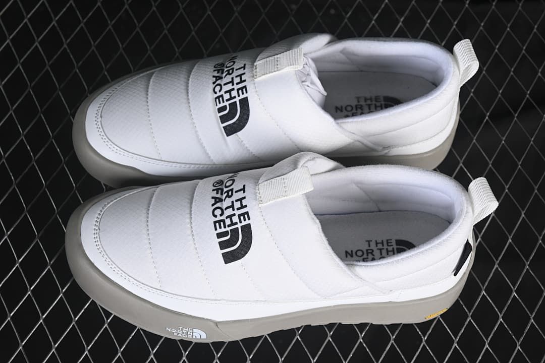 Pair of white slip-on shoes with grey outsoles viewed from above