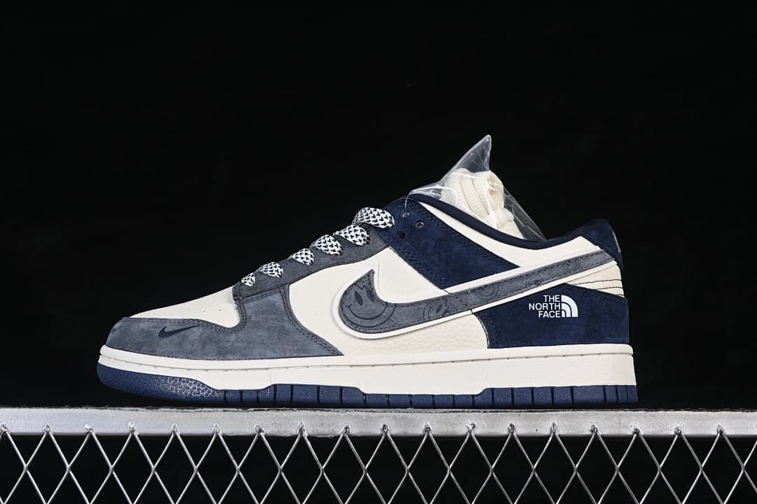 Side view of a gray, off-white, and navy low-top sneaker with patterned laces and a decorated Swoosh