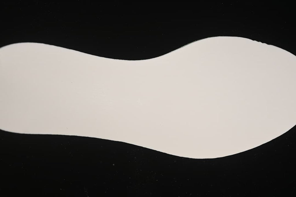 Plain white shoe-shaped insert displayed on a dark background.