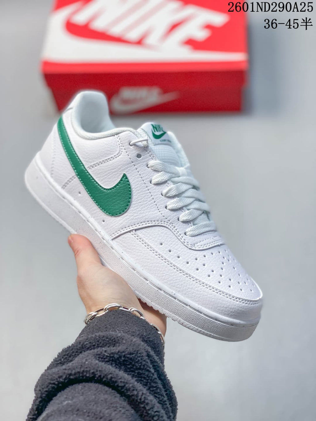 White low-top sneaker with green accents and perforated toe
