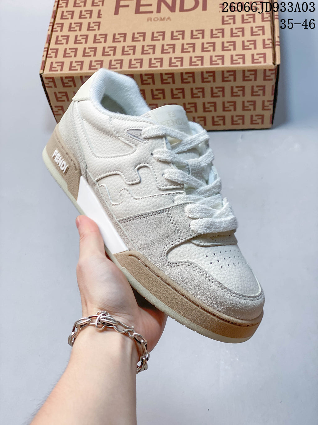 Angled side view of a white and beige low-top sneaker with a layered side detail; image overlay shows 2606GJD933A03 and sizes 35–46.