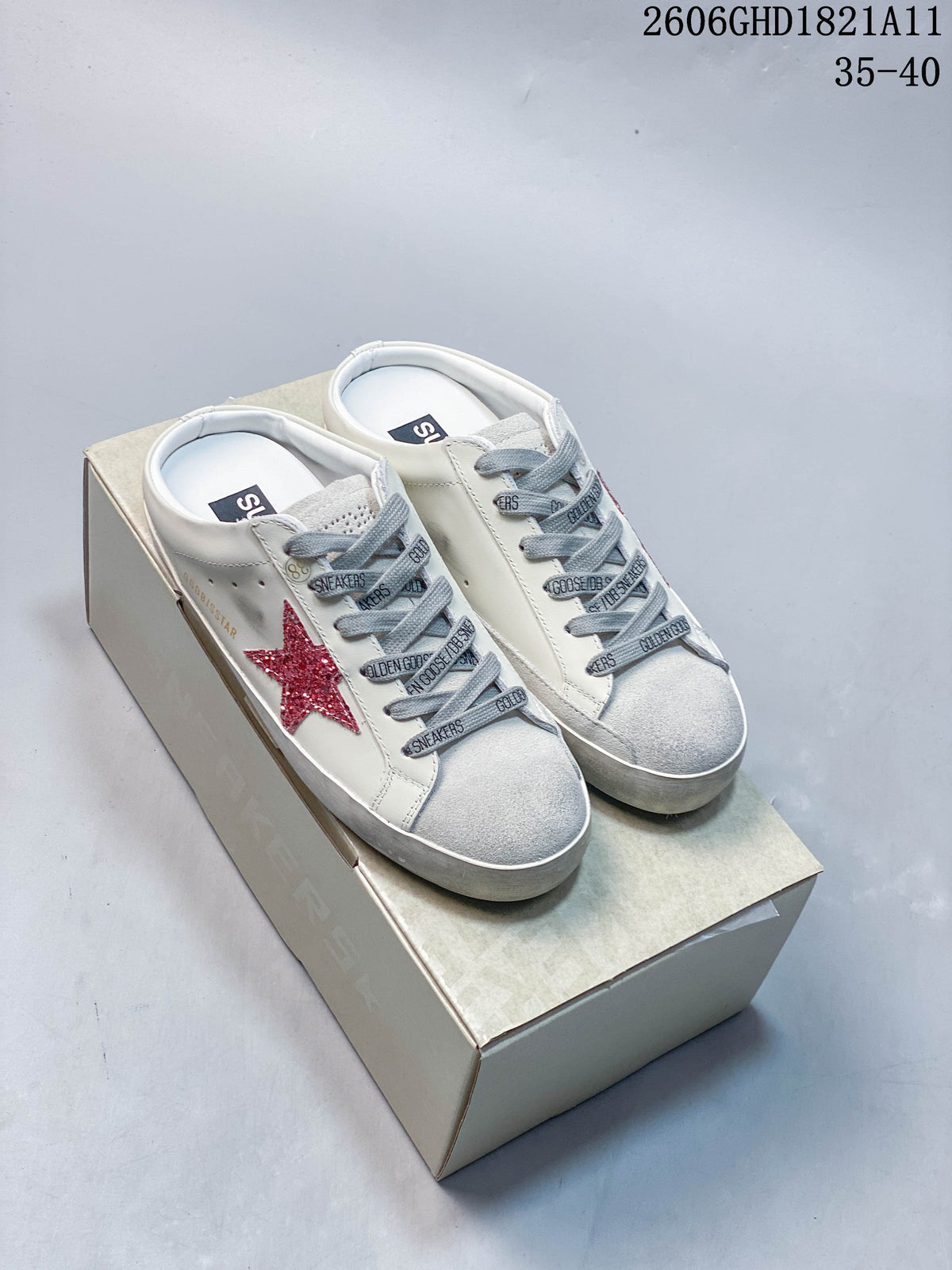Pair of white Golden Goose Super-Star low-top sneakers with red glitter stars, gray laces, and gray toe panels on a box.