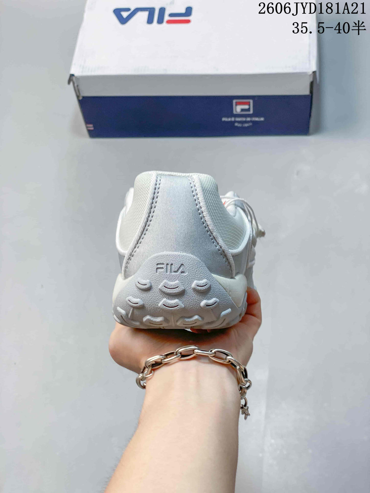 Rear view of a silver and white FILA shoe with a textured heel outsole