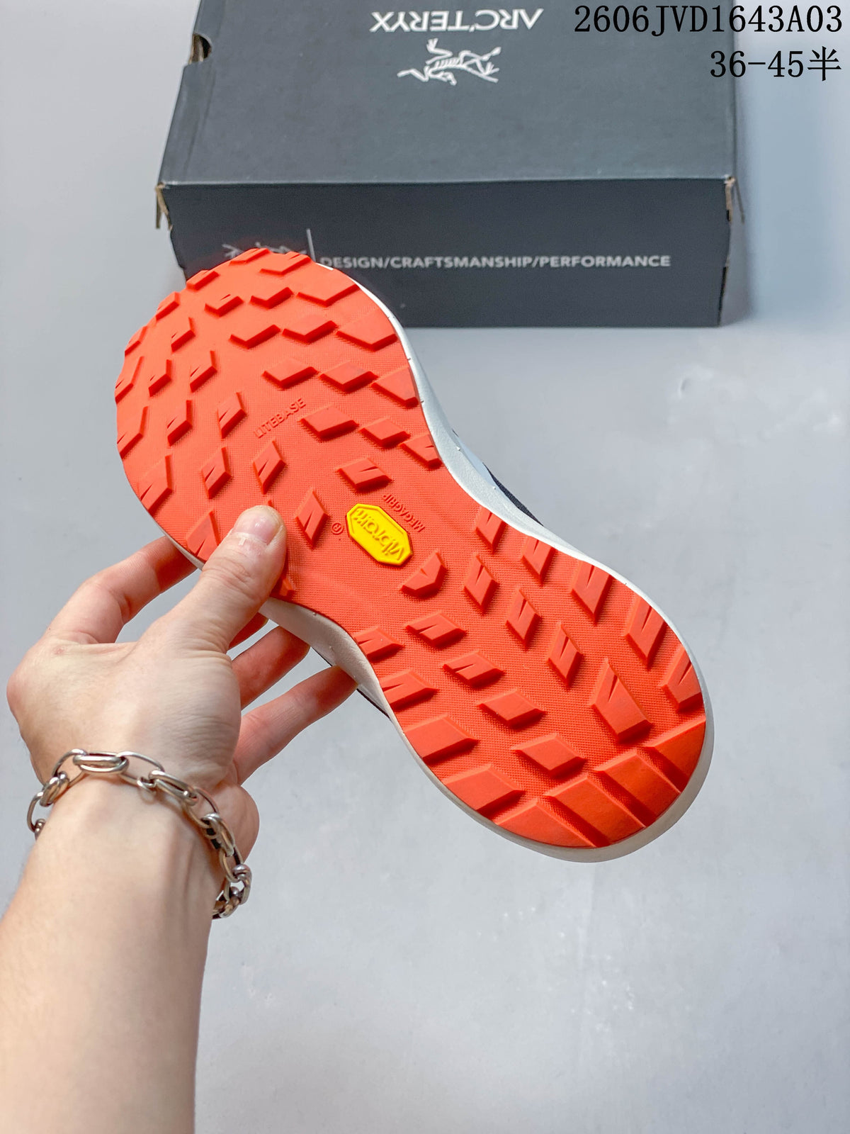 Close-up of the orange lugged outsole with a visible Vibram mark.