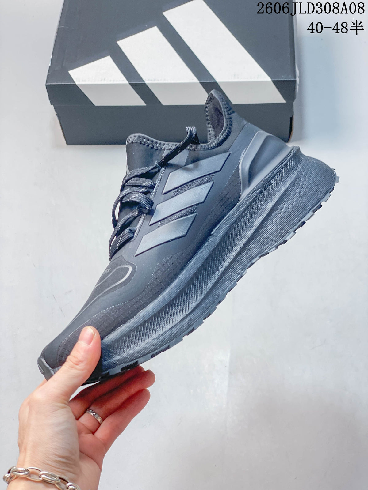 Side profile of the dark gray shoe with three-stripe detailing and a thick midsole.