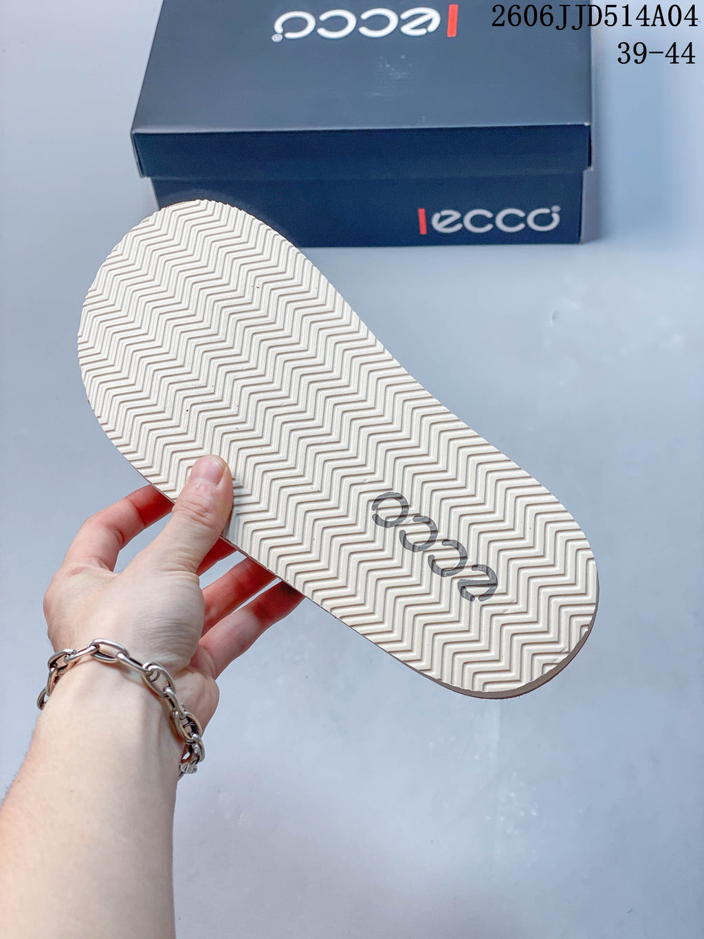 Close-up of the light-colored sandal outsole with a zigzag tread; image overlay shows 06JJD514A04 and sizes 39–44.