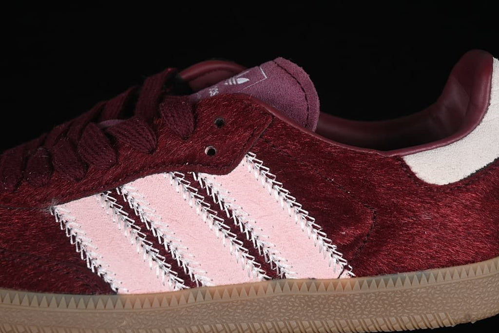 Close-up of pale pink side stripes against the burgundy upper