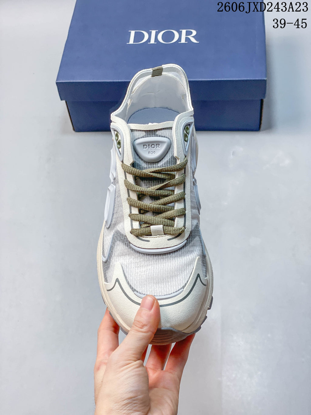 Front view of a Dior B30 sneaker with olive-toned laces and gray mesh-style panels