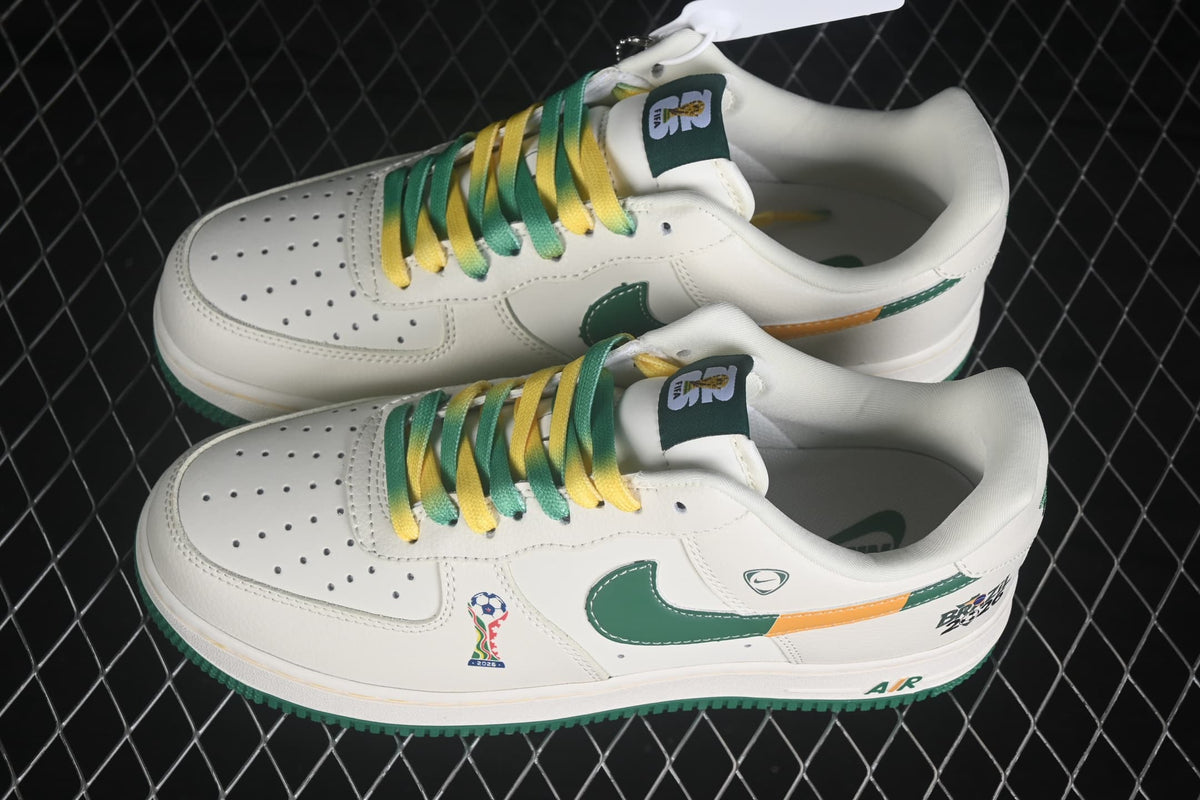 Pair of white Nike Air Force 1 '07 Low sneakers with green and yellow laces, green Swooshes, orange accents, and Brazil 2026 graphics.
