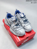 Pair of silver-toned Nike Air Monarch IV Tekno sneakers with dark blue accents and decorative chains, displayed on a red shoe box.