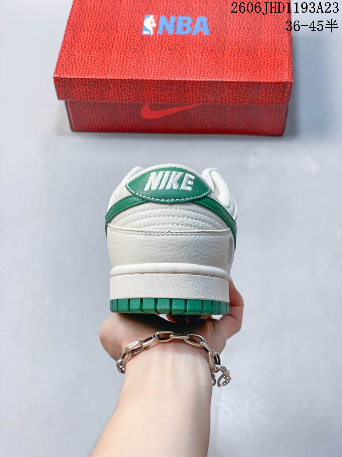 Rear view of a white and green low-top sneaker with an NBA-branded box behind it