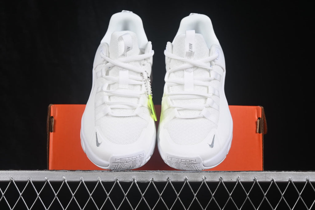 Front view of a pair of white Nike Free Metcon 7 sneakers displayed on an orange shoebox.