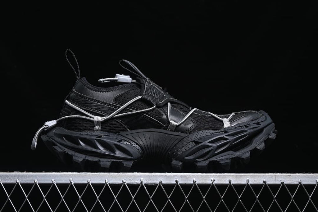 Side profile of the black low-cut sneaker with cord lacing and lugged outsole.