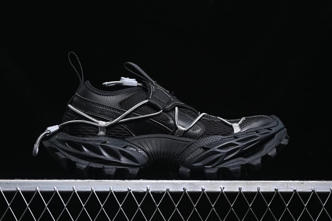 Side profile of the black low-cut sneaker with cord lacing and lugged outsole.