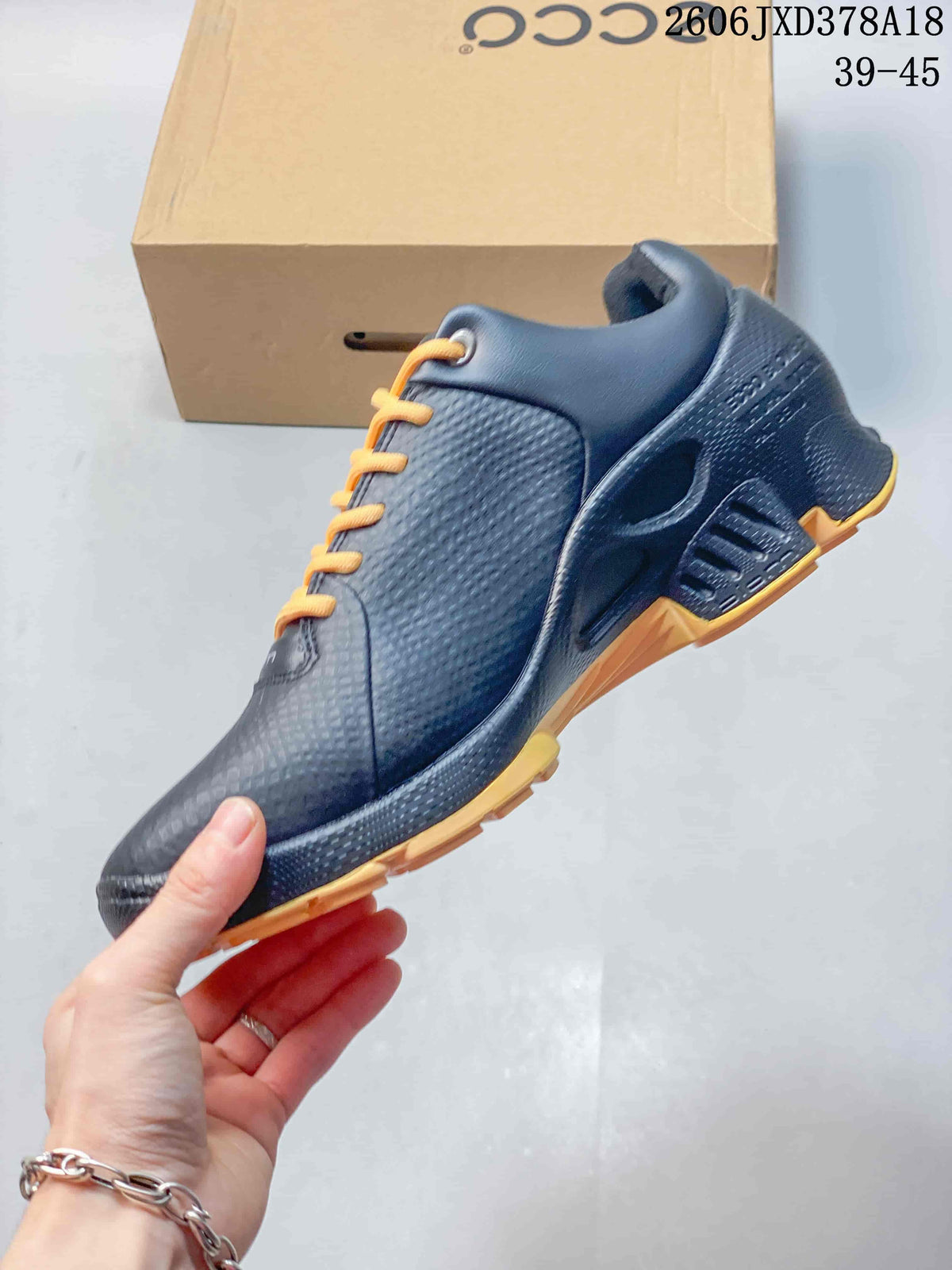 Side view of a black ECCO BIOM sneaker with orange laces and outsole accents.