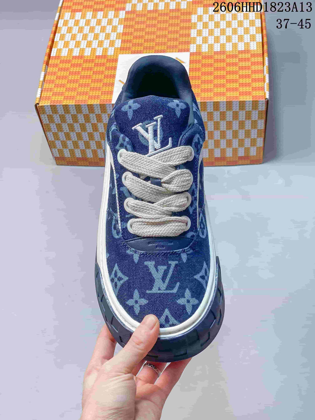 Top view of a blue patterned low-top sneaker with white laces and a logo detail on the tongue.
