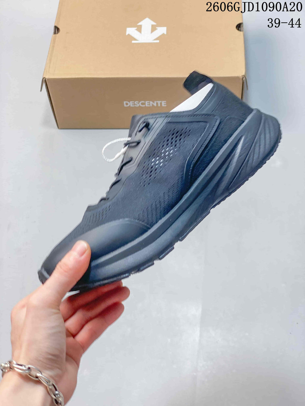 Side profile of a dark gray Descente running shoe with a textured upper
