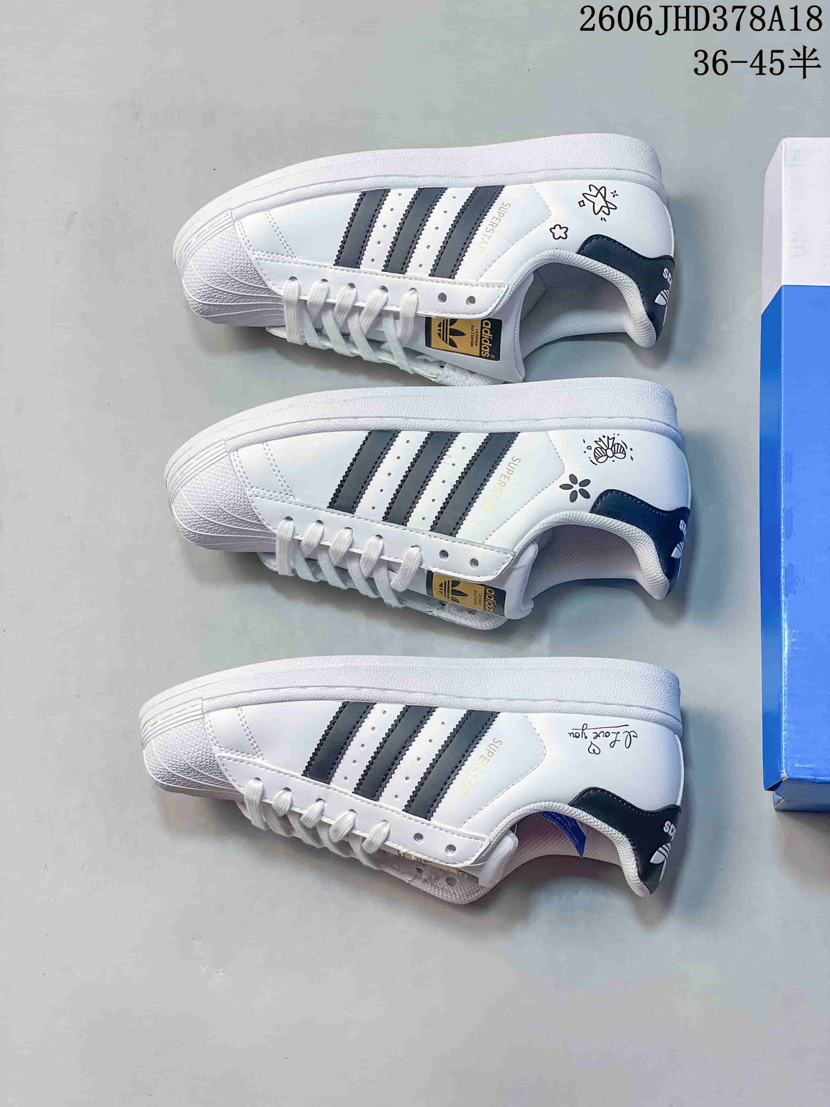 Three views of white low-top Superstar sneakers with dark stripes and decorative heel graphics