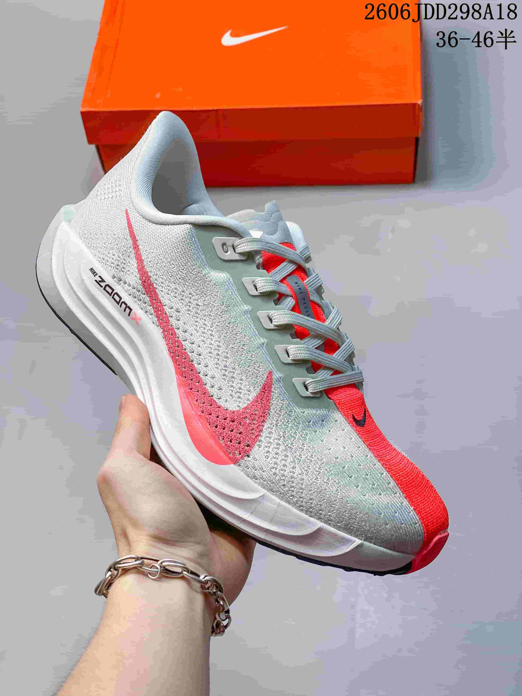 Close view of a white and coral Nike Pegasus Plus running shoe with a sculpted midsole.