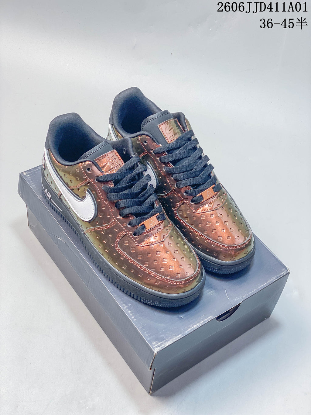 Pair of copper-toned patterned Nike Air Force 1 low-top sneakers with dark laces and white side details, displayed on a box.
