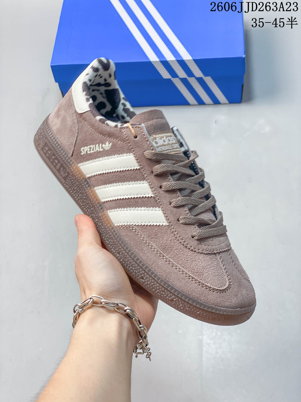 Angled side view of the taupe Adidas Handball Spezial sneaker with off-white stripes.