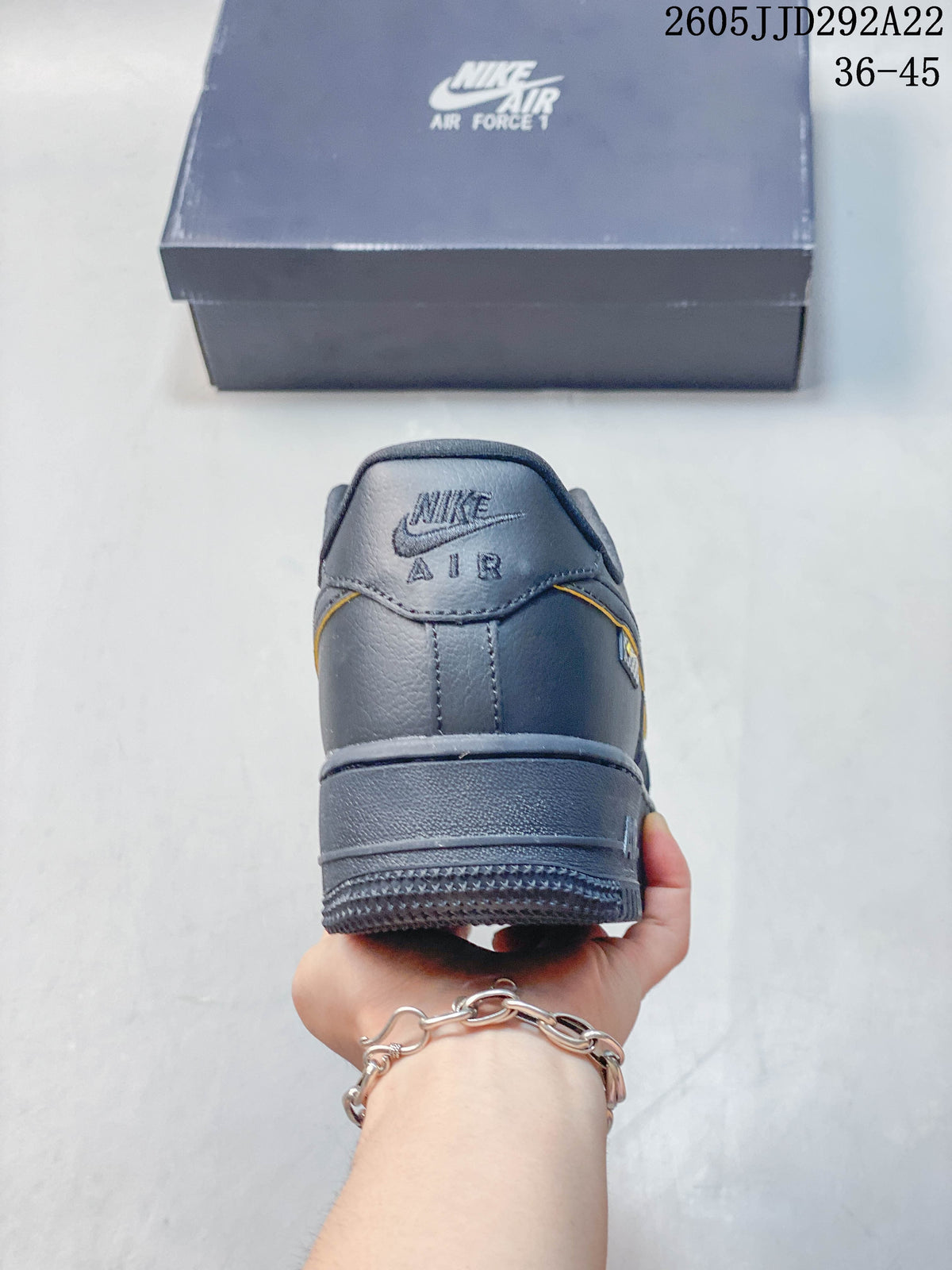 Rear view of a gray Nike sneaker with yellow trim and a raised sole
