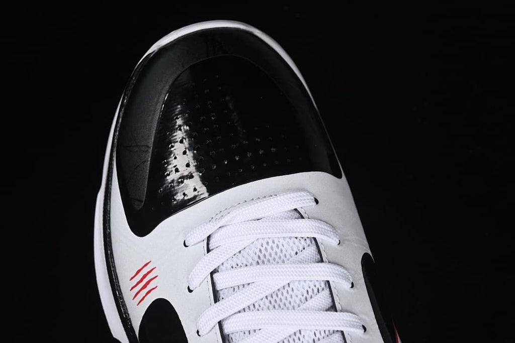 Top view of the black perforated toe, white laces and red accent marks