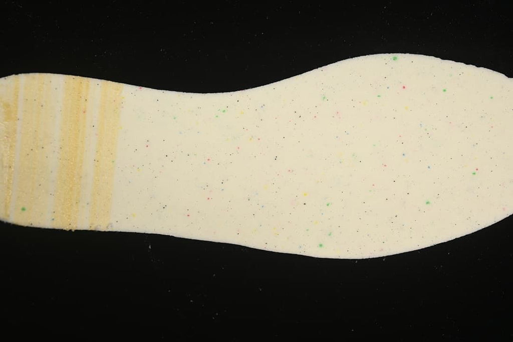 Close-up of a cream-colored shoe insole with small colored speckles.