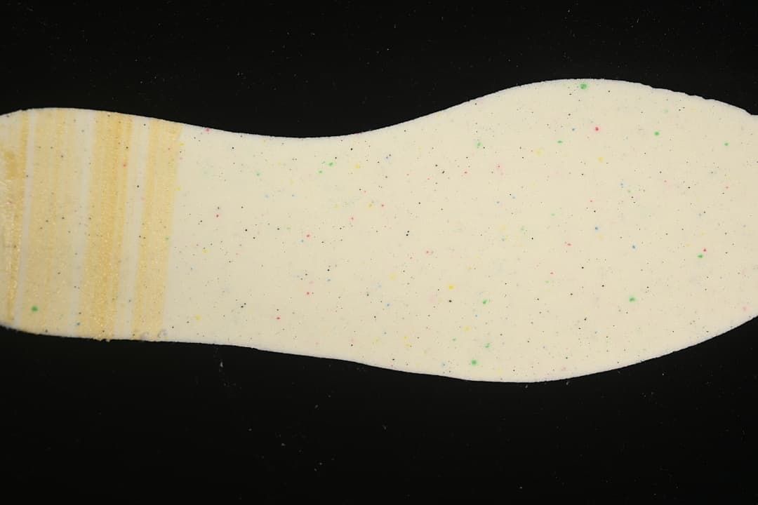 Close-up of a cream-colored shoe insole with small colored speckles.