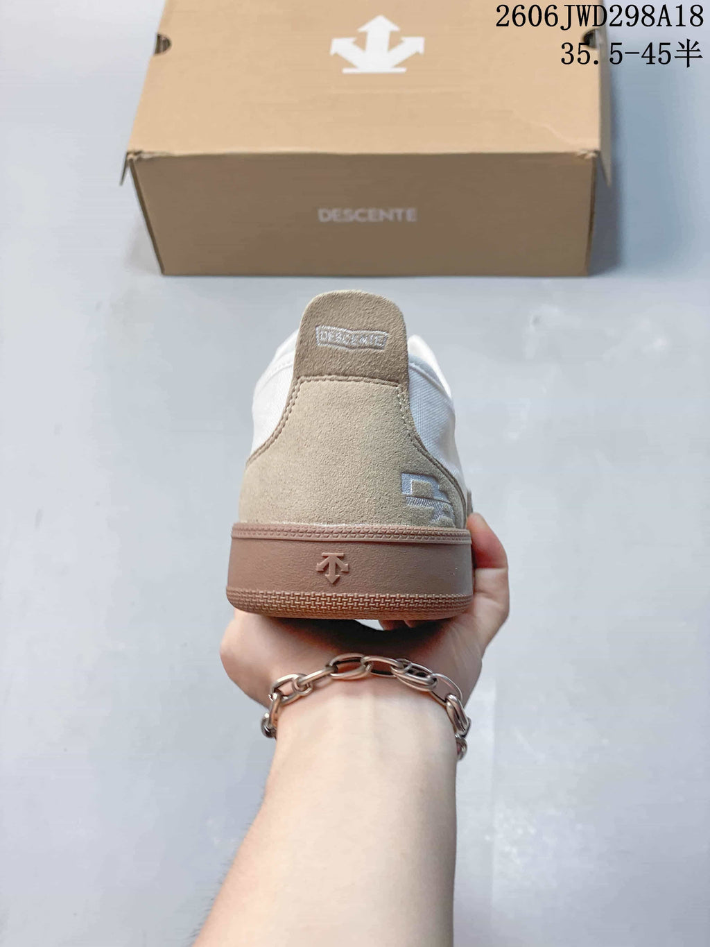 Rear view of a white and beige Descente low-top sneaker