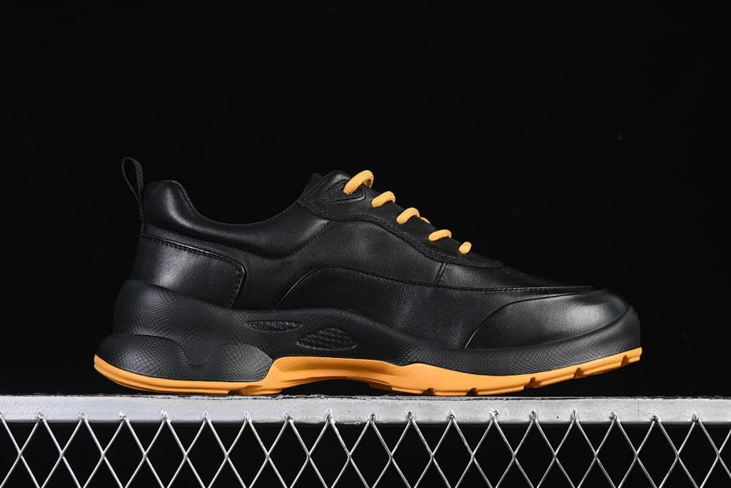 Side profile of the black sneaker with amber outsole accents