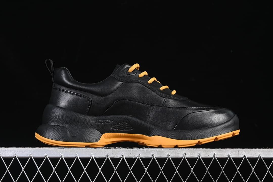 Side profile of the black sneaker with amber outsole accents